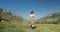 Caucasus. A young woman is walking among cows grazing in pasture in mountains