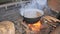 Cauldron with boiling water. Man hand with gloves open cauldron when cooking meat.