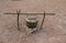 The Cauldron covered with a wooden lid is suspended from a bar for cooking over a fire