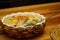 Cauliflower with bechamel sauce and melted cheese on top in ceramic dish with straw mat cover