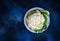 Cauliflower in a bowl with water drops on a contrasting textured blue background