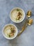 Cauliflower cream soup , decorated with fried cauliflower inflorescence in white bowls and golden spoons on a gray background.