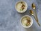 Cauliflower cream soup , decorated with fried cauliflower inflorescence in white bowls and golden spoons on a gray background. Top