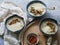 Cauliflower cream soup in three blue bowls, decorated with fried cauliflower inflorescence, red paprika powder and vintage spoons