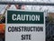 Caution construction site sign on metal fence