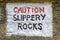 Caution Slippery Rocks sign painted on rocks, England