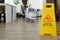 Caution of wet floor on yellow signboard in openspace office against cleaner