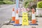 Caution yellow sign and orange traffic cones protecting excavation hole with red tape