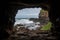 cave entrance, with view of the ocean and distant cliffs visible through the opening
