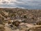 Cave houses and volcanic landscape of Cappadocian town Goreme and Uchisar castle at the horizon in the evening