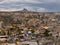 Cave houses and volcanic landscape of Cappadocian town Goreme and Uchisar castle at the horizon in the evening