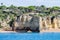 Cave and limestone arch formation. People walking crossing under the arch on the beach. Albufeira area, Algarve Portugal.