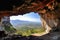 cave-in of a mountain with view of valley, surrounded by blue skies