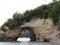 cave under a large cliff filled with trees