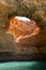 Cave in the water with natural hole in the ceiling through which natural light falling down to the water in Algarve region in