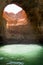 Cave in the water with natural hole in the ceiling through which natural light falling down to the water in Algarve region in