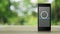 Cctv camera flat icon on modern smart mobile phone screen on wooden table over blur green tree in park, Business security and safe