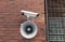 CCTV security camera and loudspeaker on brick wall outdoors