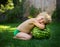 Ccute barefoot toddler boy without clothes sits on the grass next to a large striped watermelon