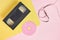cd disc and videotape on pink and yellow background, vintage video cassette and compact disc with pink label copy space