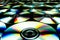 CDs / DVDs lying on a black background with colorful reflections of light.