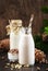 Cedar nut milk in bottles, wooden background. Non dairy alternative vegan milk and pine cones. Healthy vegetarian food and drink