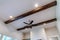 Ceiling fan with lights flanked by decorative wood beams and recessed lighting