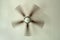 Ceiling fan with spinning blades attached to textured plaster ceiling