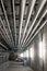 Ceiling mounted industrial pipelines inside underground  building, Long corridor with metal floors, dimly lit, no people