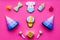 Celebrate child`s birthday. Cookies in shape of baby accesssories, party hats, gift box on pink background top view