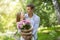 Celebrating anniversary. Young girl with flowers looking affectionately at boyfriend in park