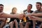 Celebrating another perfect beach day. a group of happy young friends toasting with their drinks while relaxing on the