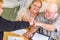 Celebrating Senior Adult Couple Give Fist Bump Over Documents in Their Home with Agent At Signing