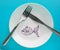 The celebration of April fool`s Day, a Plate with a fork and knife and a paper fish on a blue background. Humor