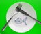 The celebration of April fool`s Day, a Plate with a fork and knife and a paper fish on a green background. Humor