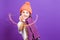 Celebration Concepts. One Expressive Winsome Caucasian Girl in Coral Winter Warm Hat and Violet Knitted Scarf Having Fun With