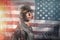 Celebration in the USA. Portrait of a female soldier posing in a half-turn on the background of the American flag. Multi-exposure