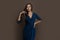 Celebrity brunette woman wearing blue evening gown standing on brown background