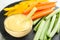 Celery and other vegetable sticks with dip sauce on slate plate, closeup