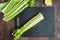 Celery stalks washed and ready to chop on a black cutting board, wood table