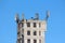 Cell phone antennas and transmitters on top of old dilapidated industrial building with metal steps on one side and clear blue sky