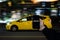 A cell phone with the the words rideshare on the screen on in front of a yellow taxi in the background.