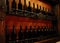 Cellar shelves with dark corked wine bottles against light brown wooden wall.