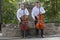 Cellist musician group perform music in the street, close up man playing violin