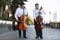 Cellist musician group perform music in the street, close up man playing violin