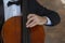 Cello close-up with a child`s hand that holds the bow.