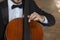 Cello close-up with a child`s hand that holds the bow.