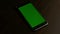 Cellphone with chroma green screen in box on wooden background, dolly move