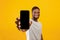 Cellphone display mockup. Happy black man showing smartphone with empty screen, recommending mobile app