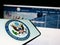 Cellphone with seal of United States Department of State (DOS) on screen in front of website.